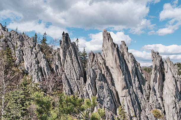 Sharp vertical rock spires known as Feathers on the southern summit of Two-Headed Hill in Taganay National Park, Southern Urals, Russia. Spring nature landscape
