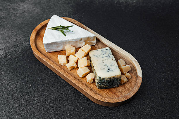 istock Gourmet cheese platter with assorted cheeses and garnish on wooden board 2219615882