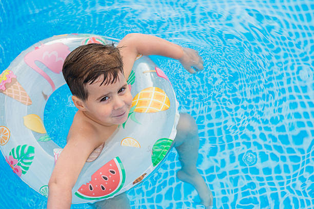 istock Playful Boy Relaxing in Swimming Float in Pool 2219616093