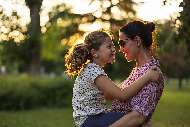 Happy mother holding and spinning her cute daughter in nature at sunset