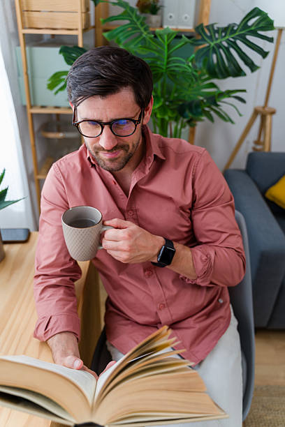 istock Man enjoying a cup of coffee while reading a book 2219621450