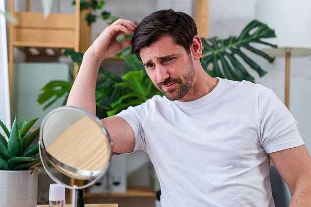 istock man checking his hair loss in the mirror 2219621652
