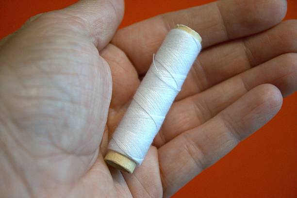 White thread in hand withred  background.