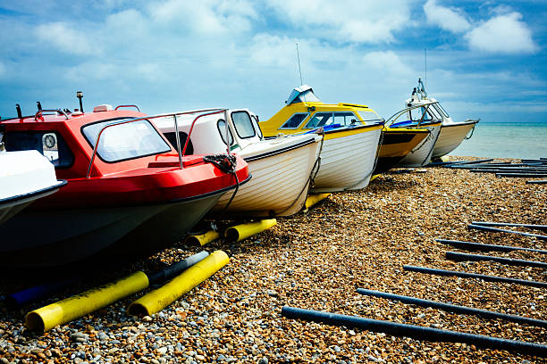 Nautical vessels in a row on a pebble beach in Eastbourne, East Sussex, UK.