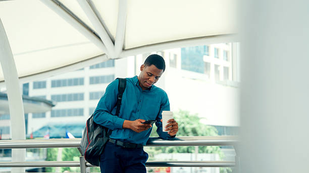 istock African-American Businessman using smartphone and holding coffee in urban setting 2219625992