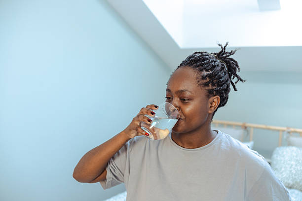 istock Woman drinking water in a light room during a relaxing moment 2219628965