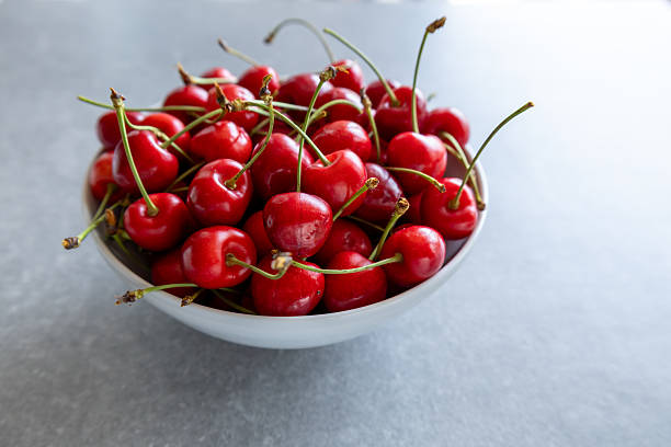 istock fresh red cherries in a white bowl on gray background, side view 2219629481
