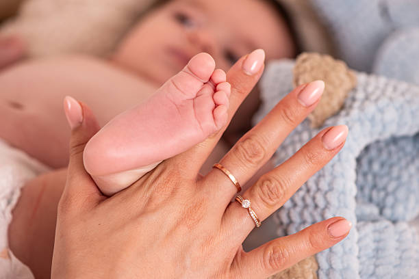 A close up image of a newborn's tiny feet wearing wedding rings.