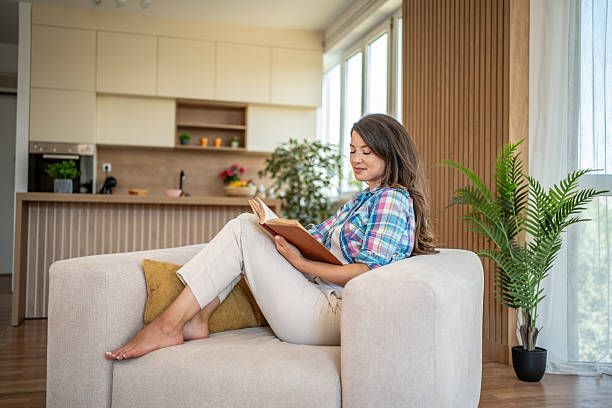 istock Woman relaxing on sofa reading a book in modern apartment 2219634331