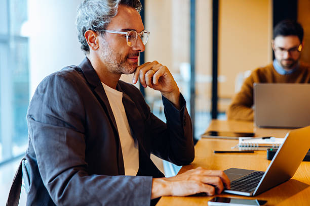 istock Man working on laptop at a desk in a bright office 2219635478
