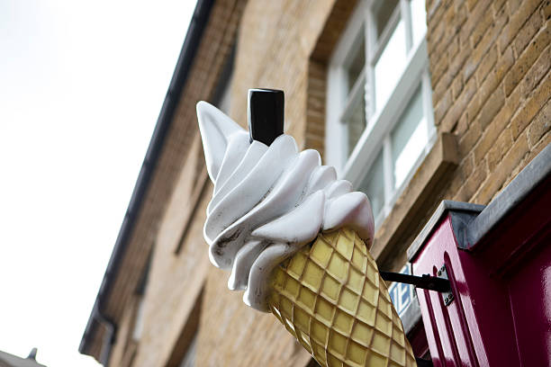Large ice cream cone with a chocolate flake outside a shop viewed from a low angle