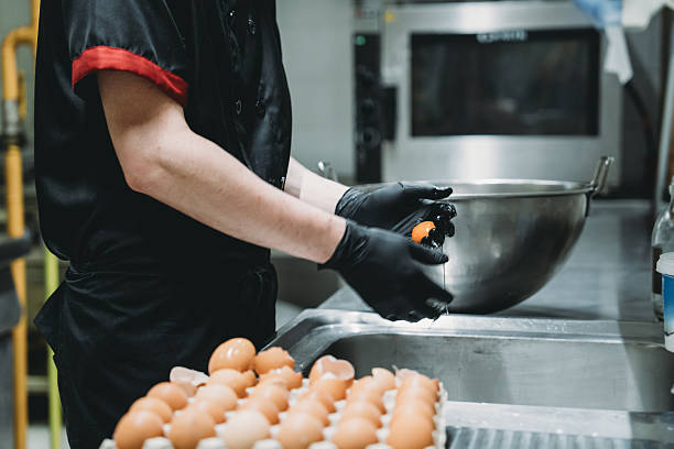 istock Chef cracking eggs into stainless steel bowl in professional kitchen 2219639972
