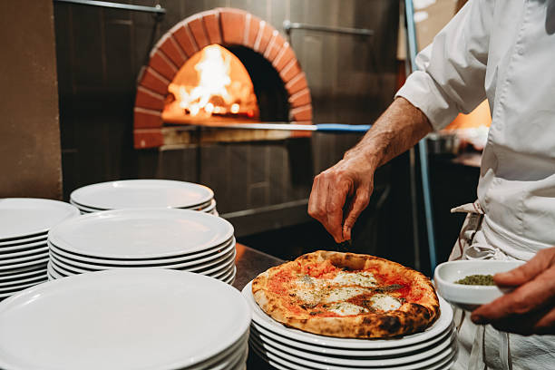 istock Chef sprinkling spices on a Neapolitan pizza in a restaurant kitchen 2219639989