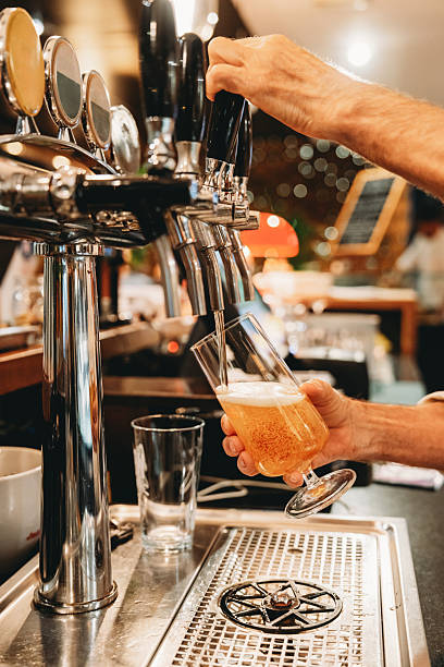 istock Bartender pouring a fresh beer from tap in a glass 2219640014