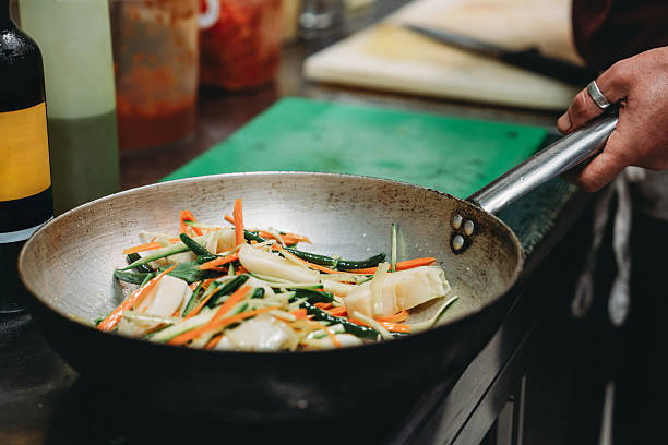 Close-up of a chef cooking fresh vegetables in a pan, adding a touch of culinary expertise to the vibrant ingredients