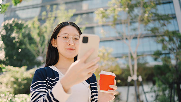 istock asian woman using digital tablet outdoors surrounded by green representing portable business tech and digital access  flexible business environments, and modern lifestyle technology. 2219640142
