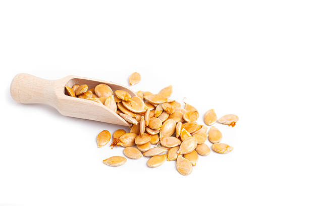 istock Pumpkin seeds on a wooden spoon and on a white background 2219640415