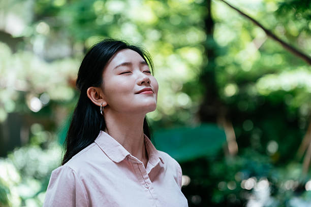 istock Young Asian woman with eyes closed, relaxing and taking a deep breath while having a break from work outdoors. 2219640827