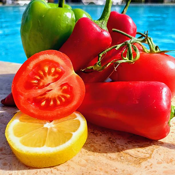 Lemon, tomatoes, red and green peppers standing by the swimming pool.