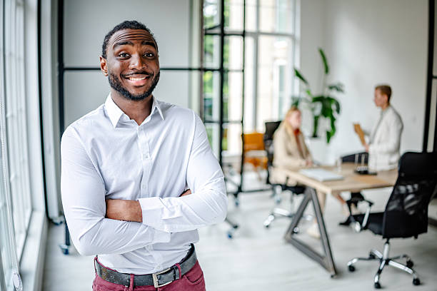 istock Young black leader exudes confidence in modern office setting with diverse team collaborating nearby 2219643651
