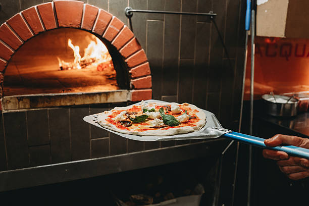 istock Chef placing pizza with mozzarella and basil into wood fired oven 2219644181