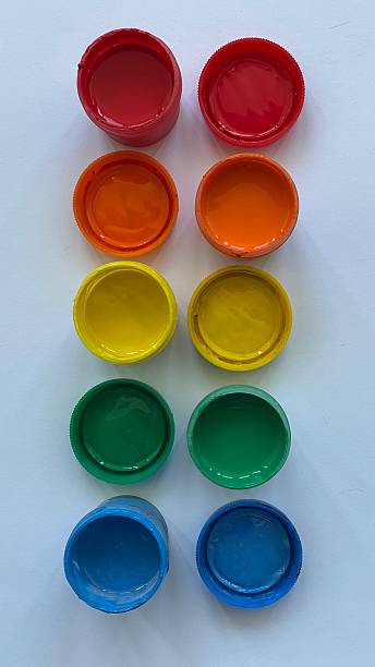 istock Open jars of bright gouache paint arranged in rows on white background. Colorful palette including red, orange, yellow, green, and blue. Art supplies concept for school, creativity, and design. 2219645244