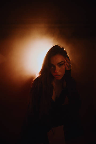 istock Young woman posing in a dark room with orange light 2219648281