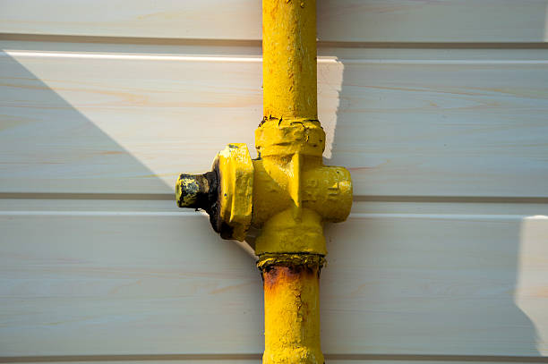 istock A yellow pipe fitting connects to a vertical pipe against a white wall, illuminated by soft sunlight emphasizing its details 2219649371