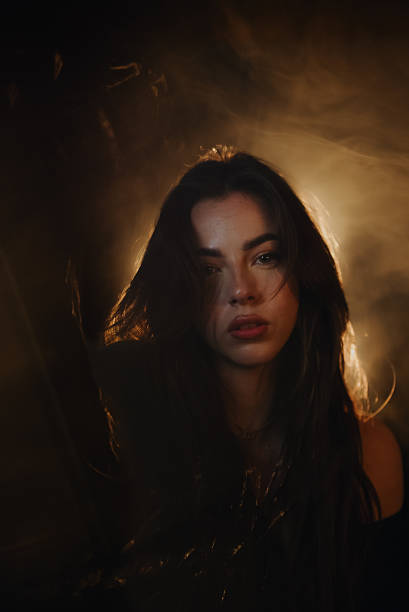 istock Young woman posing in a dark and smoky environment with dramatic lighting 2219650120