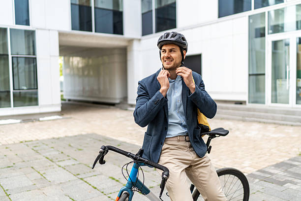 istock Businessman wearing helmet adjusting his shirt while sitting on his bicycle 2219652053