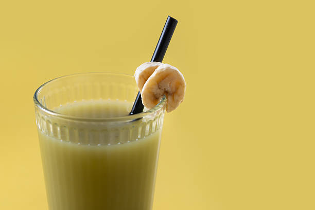 Green smoothie with spinach,banana, apple, and lemon on yellow background