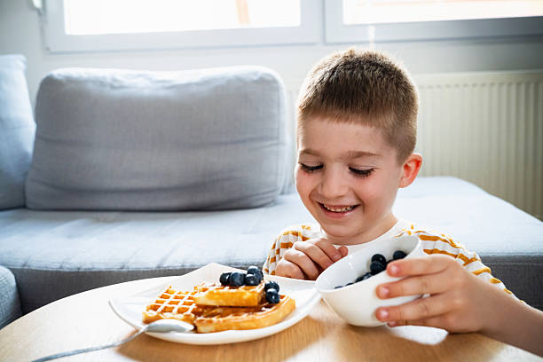 istock Smiling boy enjoying waffles with fresh blueberries at home 2219652499