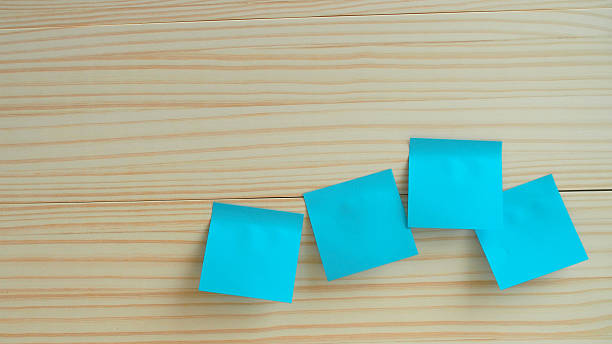 Four turquoise sticky notes arranged casually on a clean light wood surface. Ideal image for productivity themes, office inspiration, planning, or creative brainstorming