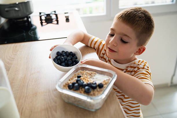 istock Young boy preparing a blueberry and granola breakfast in a bright kitchen 2219652993