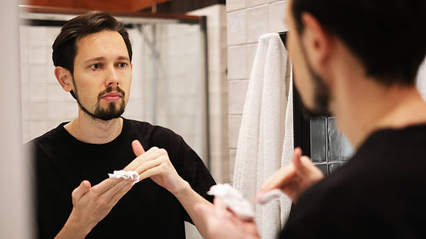istock Young man applying shaving foam to cheeks while looking in mirror 2219654257