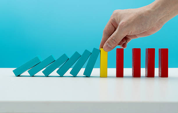 istock Man hand stopping the dominos falling 2219658167