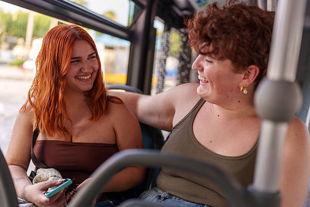 istock Two young women laughing and talking while traveling by bus 2219658440