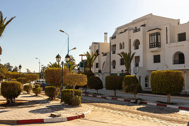 A white building with architectural details stands amidst greenery under a clear blue sky in Port El Kantoui - Sousse - Tunisia - Africa