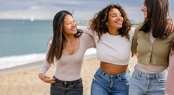istock Three happy young women walking on beach, enjoying sunny day 2219660617