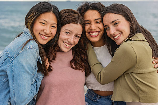 istock Four young women embracing and smiling at the beach 2219660632