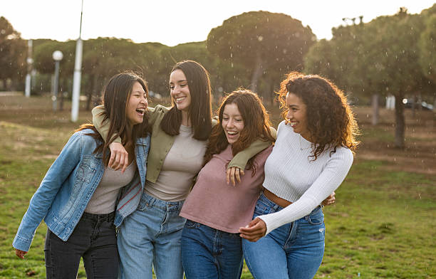 istock Four young women laughing and hugging in a park 2219660664