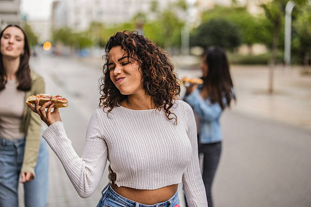 istock Young woman smelling pizza slice outdoors with friends 2219660751