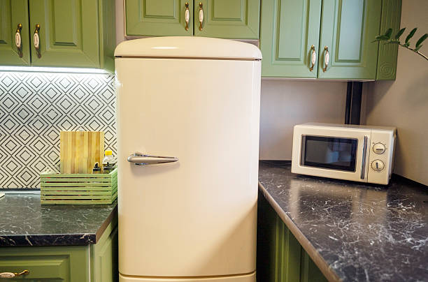 istock Light beige refrigerator and microwave and green kitchen cabinets 2219661482