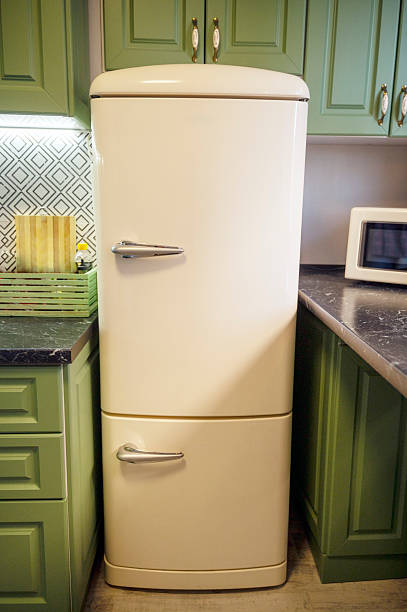 istock Light beige refrigerator and microwave and green kitchen cabinets 2219661791
