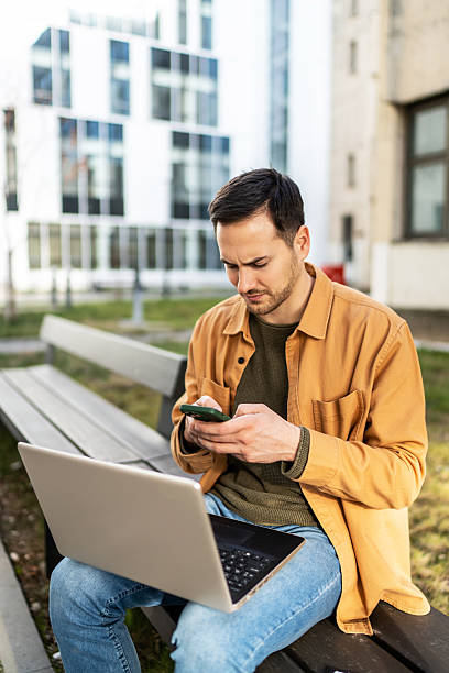 istock Freelancer working remotely on a bench with laptop and smartphone 2219662302