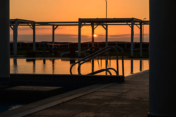 Beautiful sunset sky mirrored on the calm surface of a swimming pool, creating a serene and peaceful atmosphere.