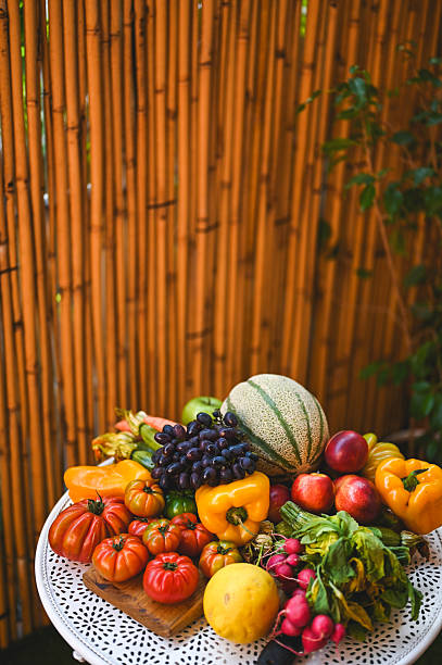 Fresh seasonal fruits and vegetables arranged on a table in a garden setting
