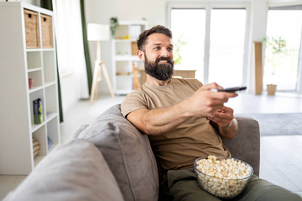 istock Man Flipping Channels with Popcorn in Hand 2219669619