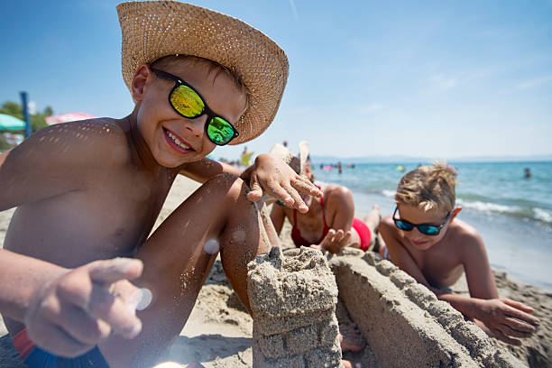 istock Happy children building sandcastles on a beach on a sunny day 2219670145