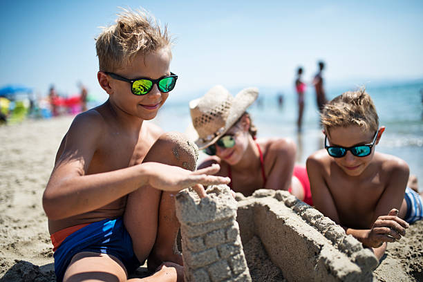 istock Happy children building sandcastles on a beach on a sunny day 2219670161